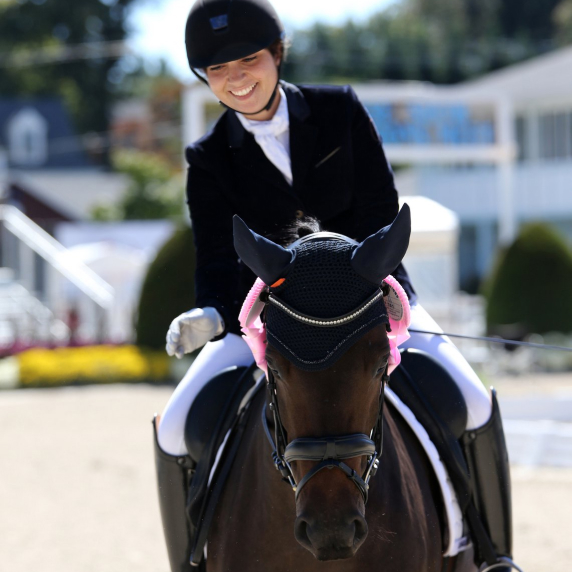 A woman on a dark brown horse smiles because her horse is good.